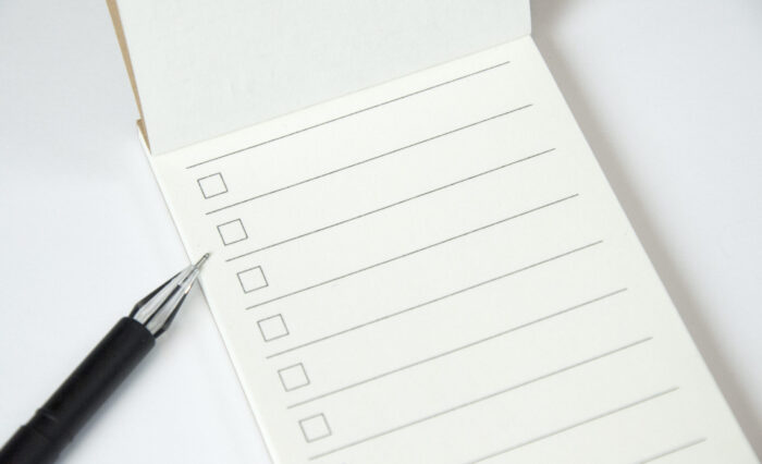 Blank to do list planner with checklist and black pen on white background, close up view